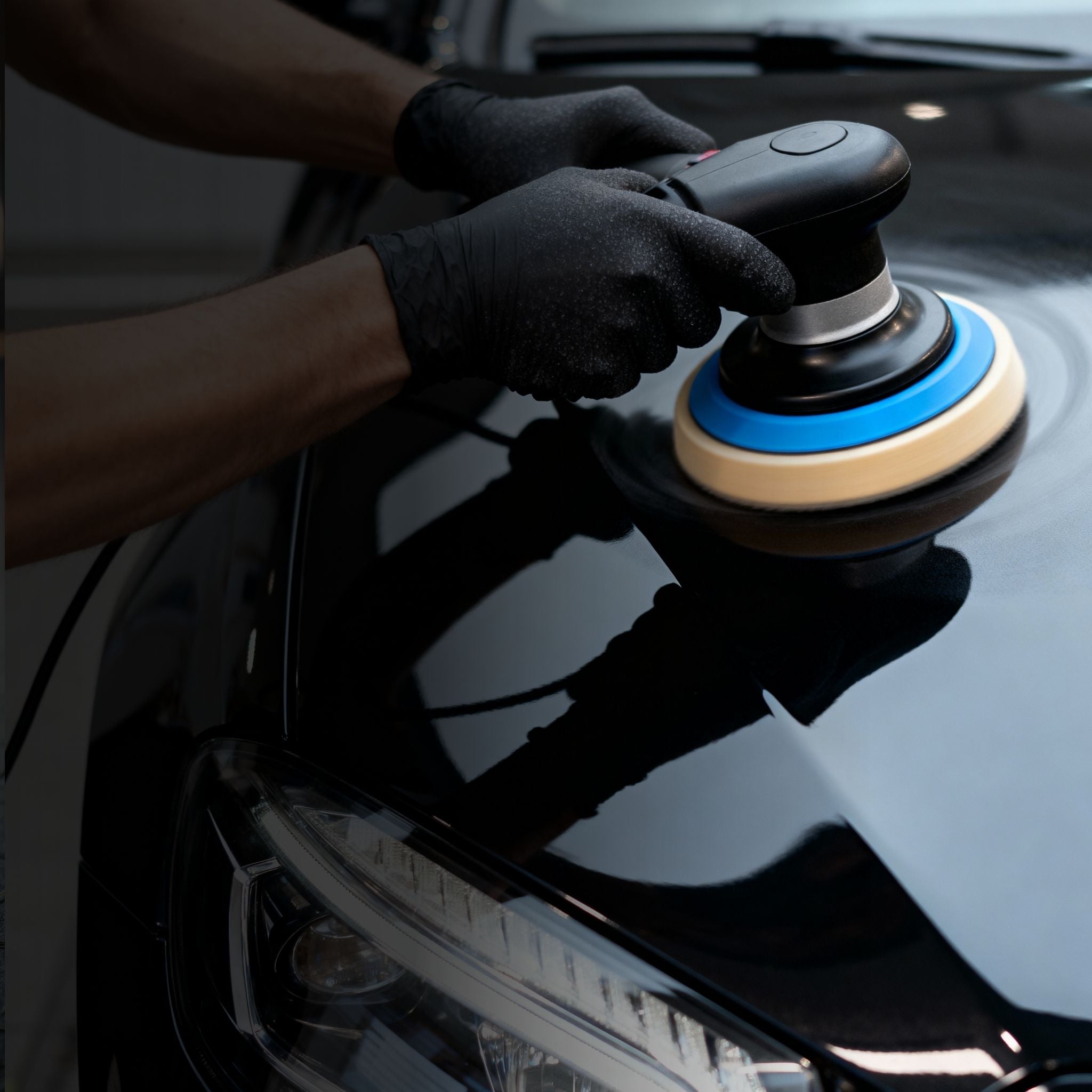 Person using a car polisher on a black car